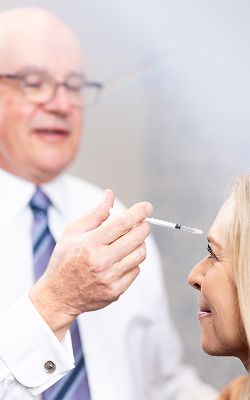 Smiling surgeon in surgical environment with lights.