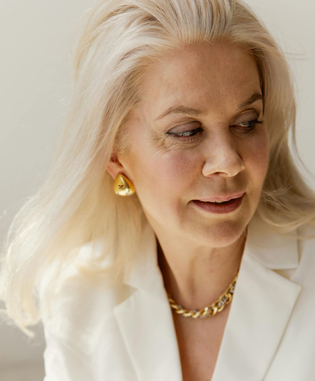 Woman with long blonde hair and elegant jewelry.
