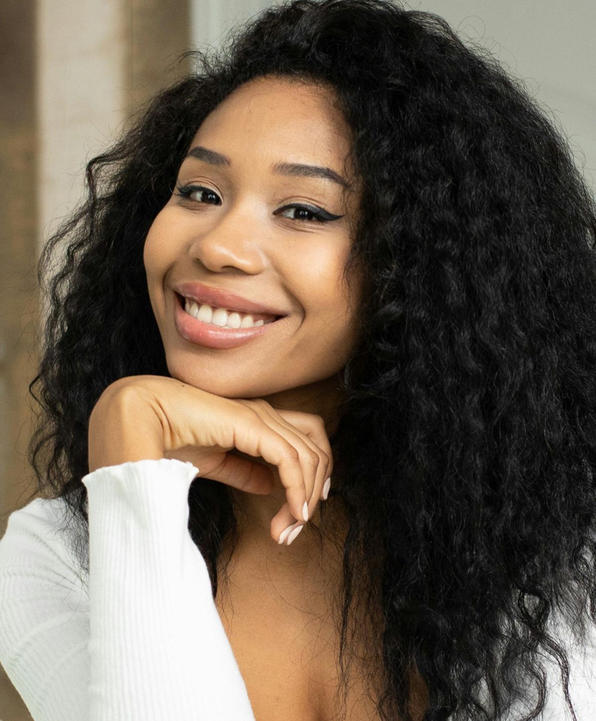 Smiling woman with curly hair and white top.