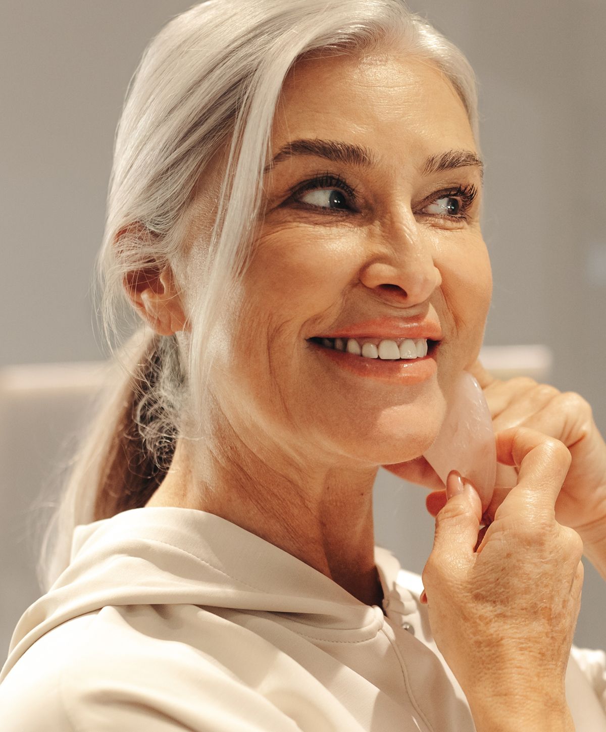 Smiling woman using a beauty tool on her face.