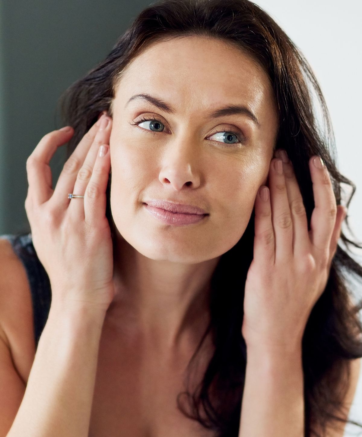 Woman gently touching her face and smiling.