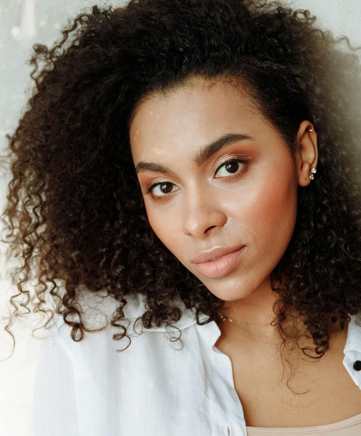 Woman with curly hair and natural makeup.