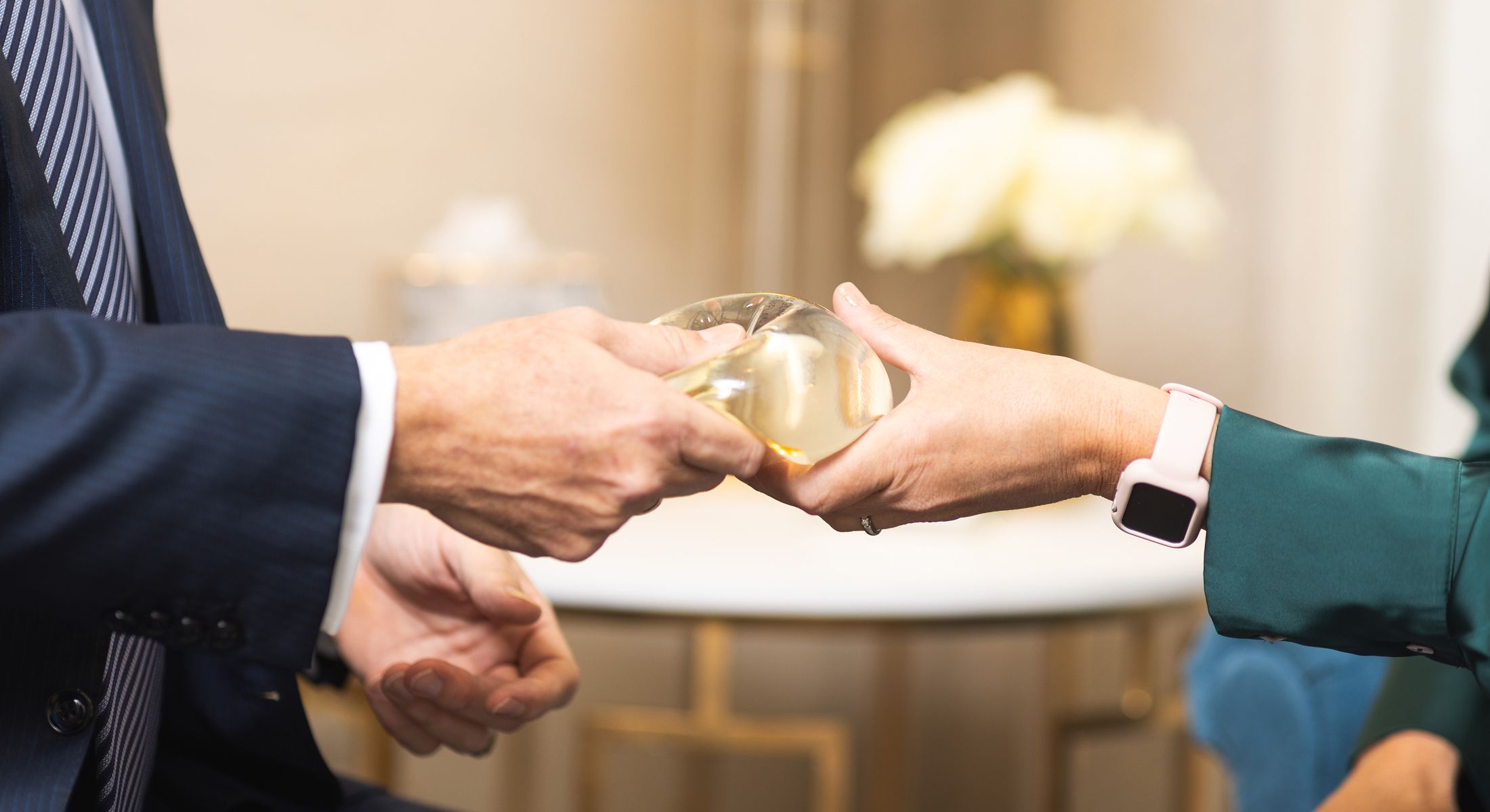 Hands exchanging a transparent glass object.