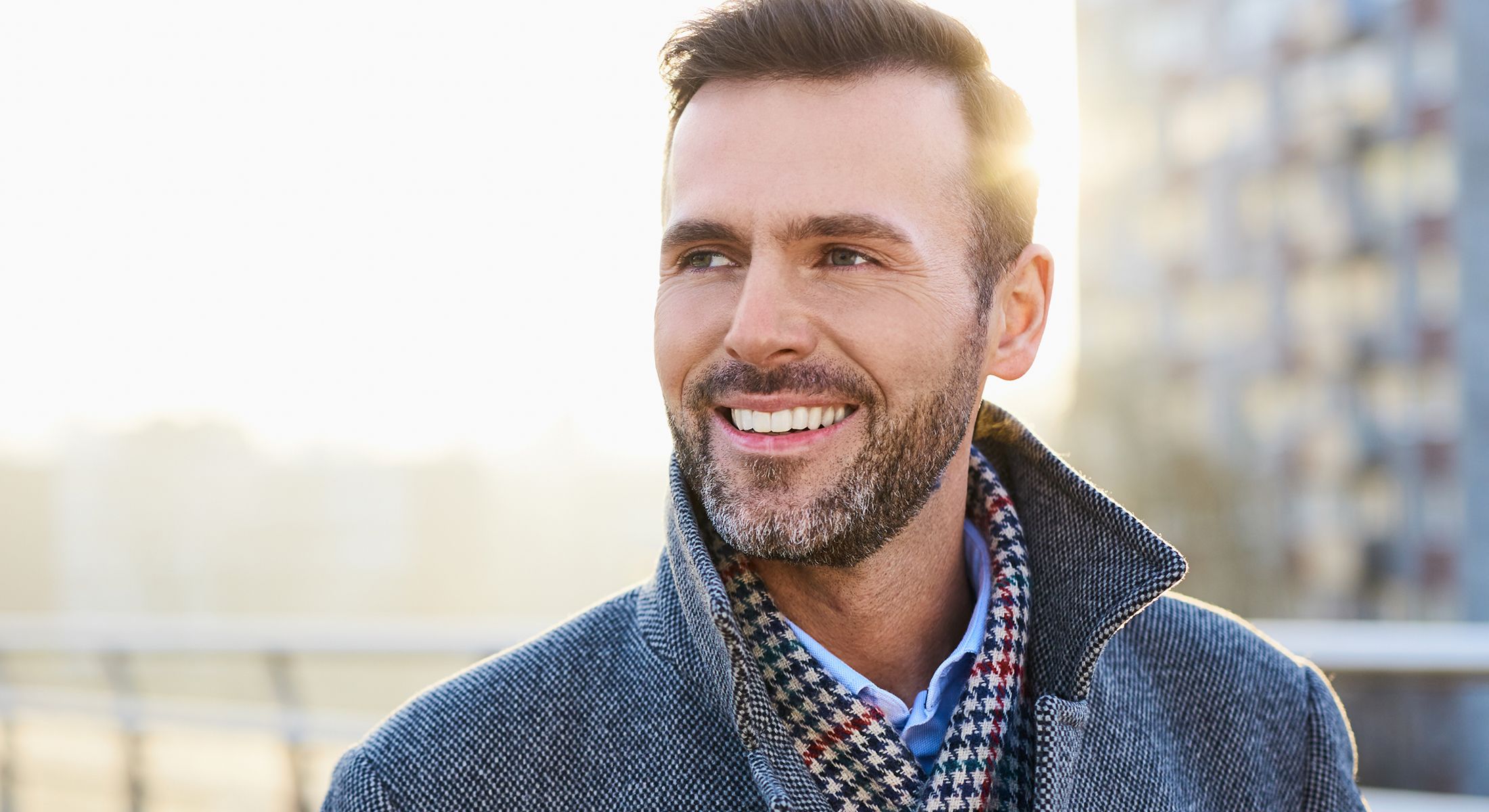 Smiling man in stylish coat outdoors.