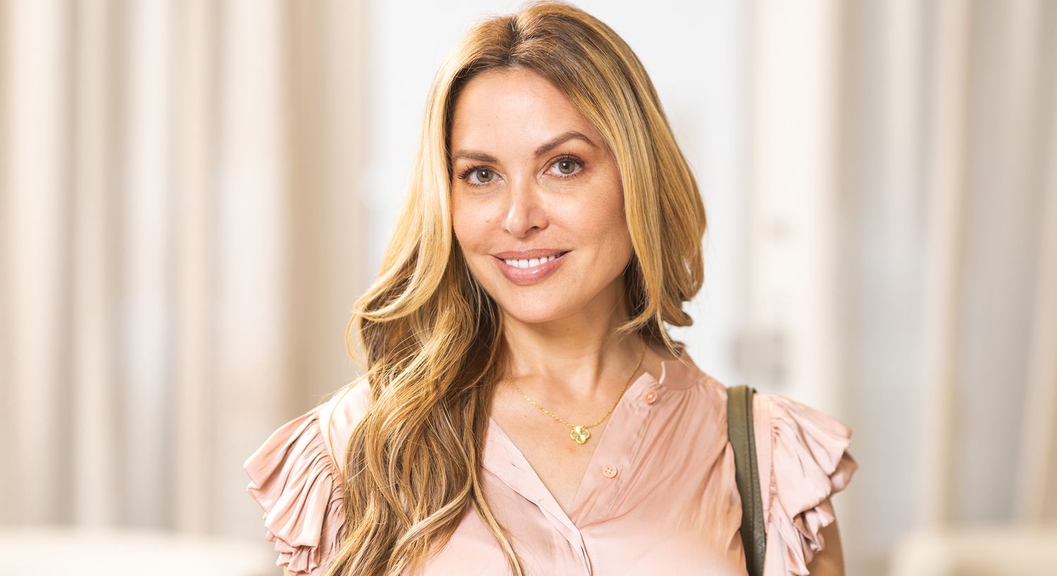 Smiling woman in a light pink blouse.