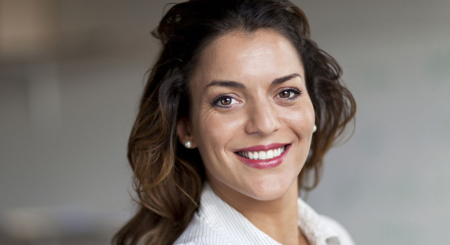 Smiling woman with long hair and earrings.