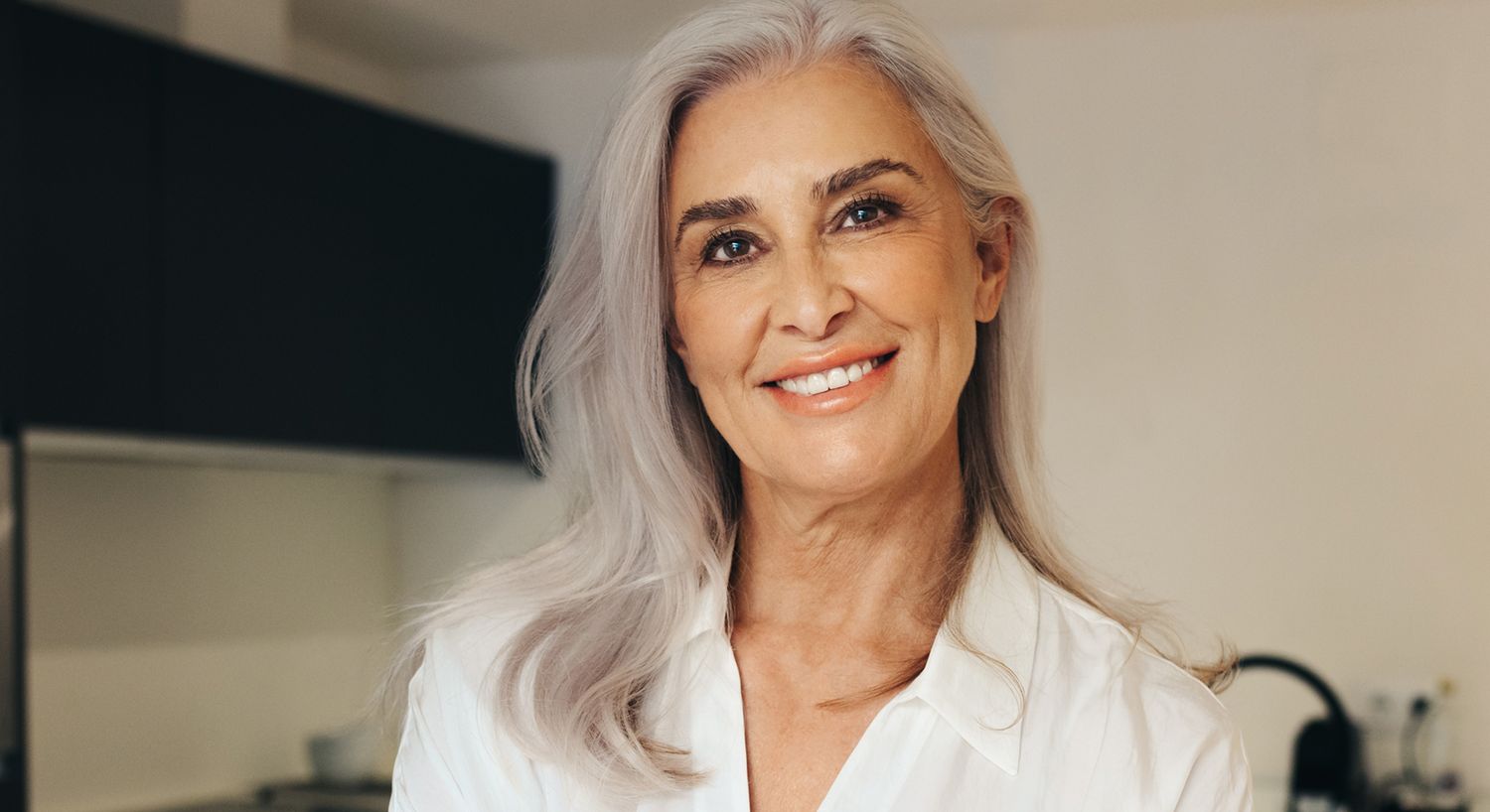 Smiling older woman in a bright kitchen.