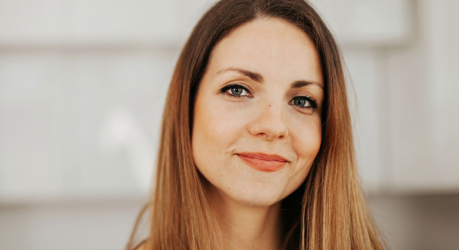 Smiling woman with long hair indoors.